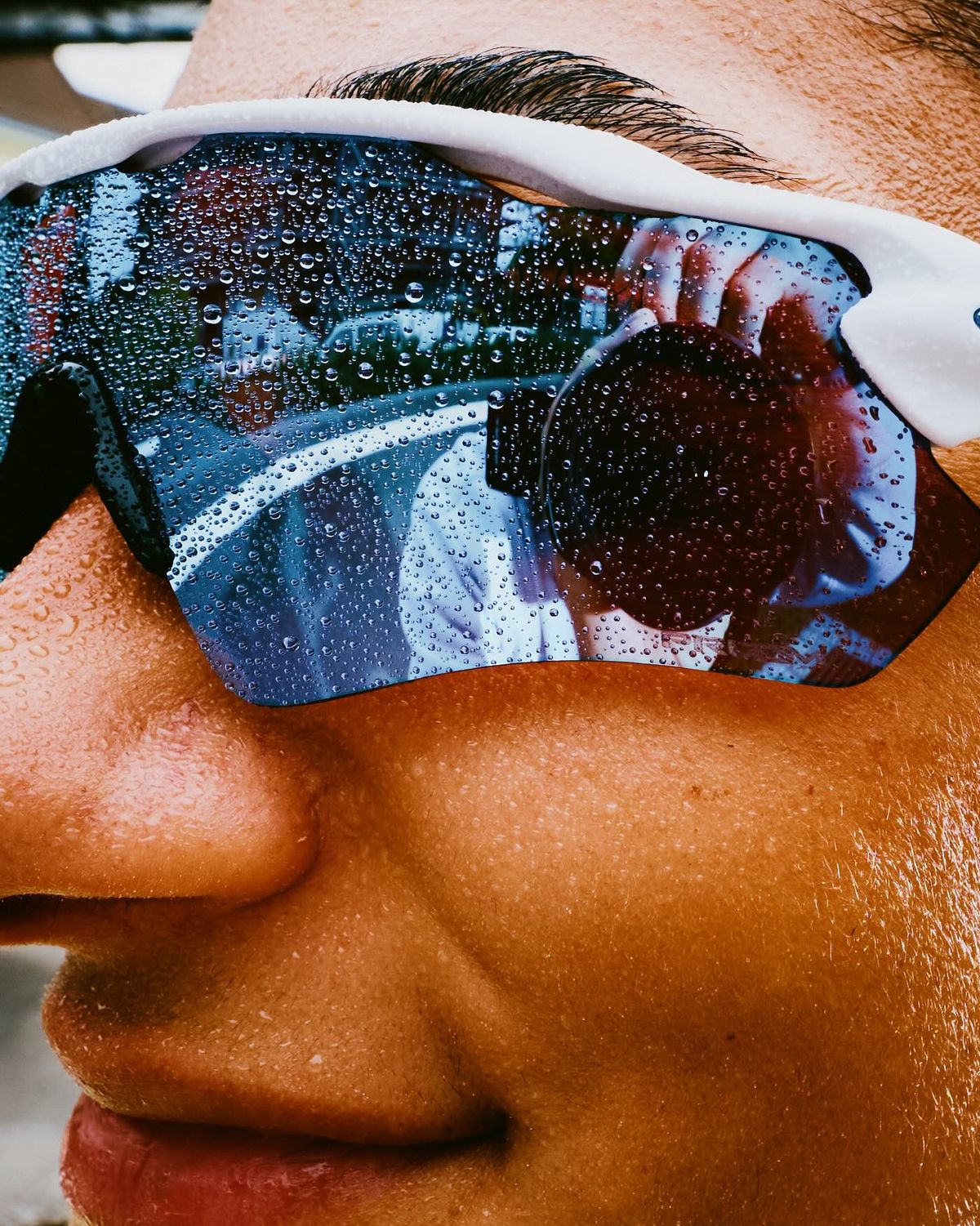 Close-up of a runner’s face, sweat beaded across her sunglasses